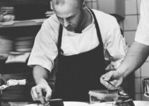 chef adding ingredients to a plate in restaurant kitchen black and white photo