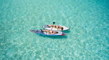 two women relaxing on kayaks in crystal clear water